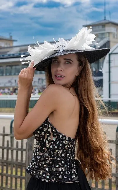 Capeline en paille tressée de couleur noire avec une décoration en plumes blanches